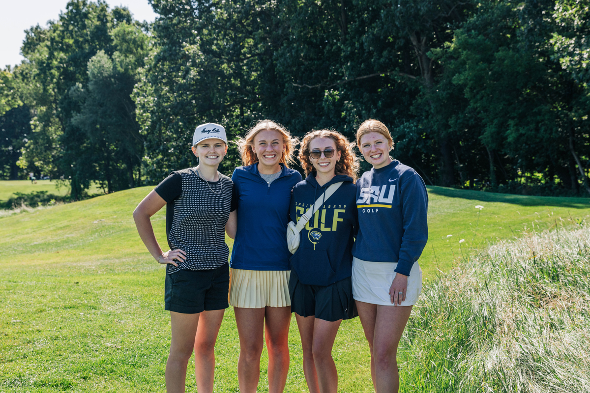 Female SAU student posing for a group picture on the golf course smiling.